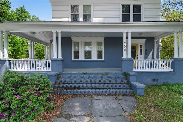 property entrance featuring covered porch and brick siding