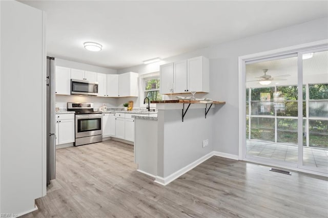122 Kendall Dr, Newport News, VA 23601 - kitchen featuring visible vents, baseboards, light wood-style floors, white cabinetry, and stainless steel appliances