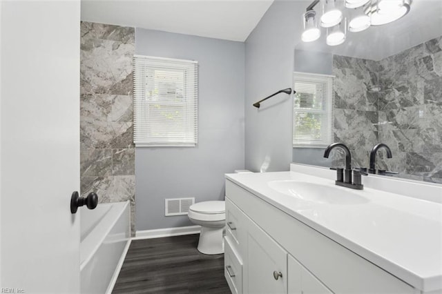 122 Kendall Dr, Newport News, VA 23601 - bathroom featuring vanity, toilet, a washtub, visible vents, and wood finished floors