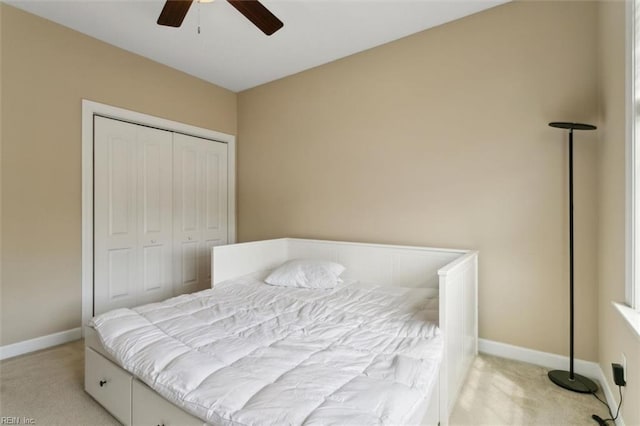 carpeted bedroom with a closet, baseboards, and ceiling fan
