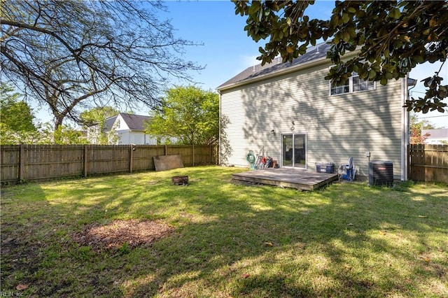 back of house featuring central AC unit, a fenced backyard, and a lawn
