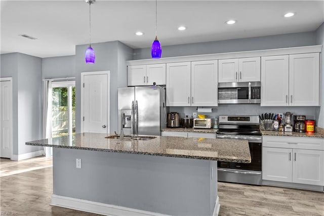 kitchen with dark stone countertops, visible vents, a sink, appliances with stainless steel finishes, and white cabinetry