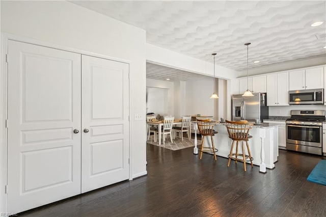 209 Cobblestone Reach Reach, Suffolk, VA 23435 - kitchen with dark wood finished floors, a kitchen bar, white cabinetry, appliances with stainless steel finishes, and hanging light fixtures
