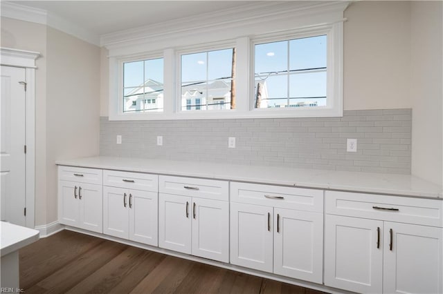 kitchen featuring light stone counters, dark wood-style floors, crown molding, backsplash, and white cabinets