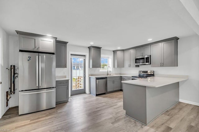 9289 Gates Rd, Suffolk, VA 23437 - kitchen with a sink, a peninsula, gray cabinetry, stainless steel appliances, and light wood-style flooring