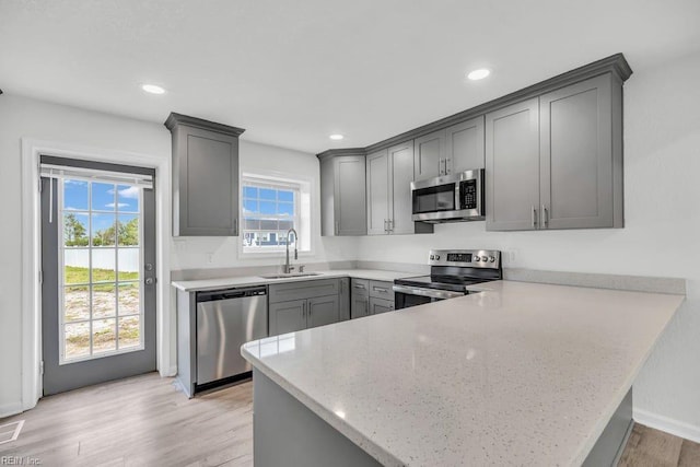 9289 Gates Rd, Suffolk, VA 23437 - kitchen with a peninsula, light wood-type flooring, appliances with stainless steel finishes, a sink, and gray cabinetry