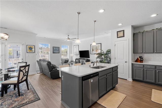 kitchen featuring stainless steel dishwasher, a sink, gray cabinetry, light countertops, and ornamental molding