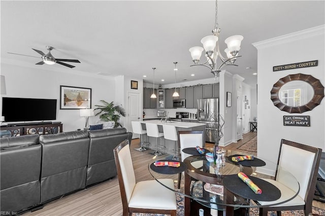 dining space with recessed lighting, crown molding, baseboards, light wood-style flooring, and ceiling fan with notable chandelier