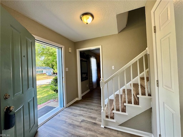 entryway featuring a textured ceiling, wood finished floors, and stairs