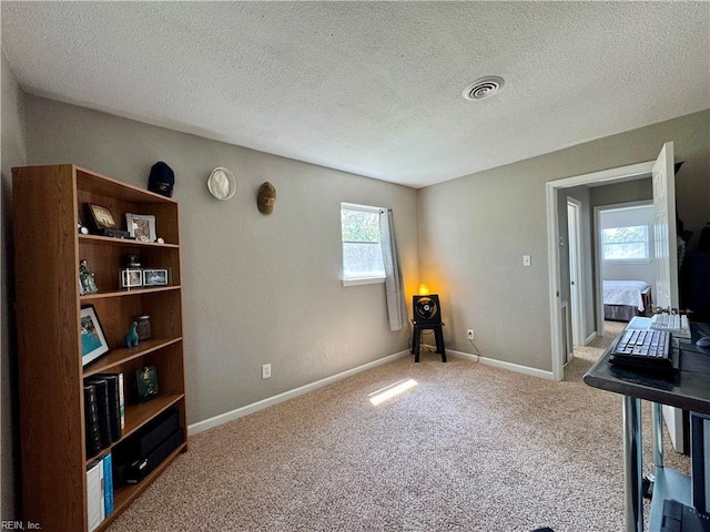interior space featuring a textured ceiling, visible vents, and carpet flooring