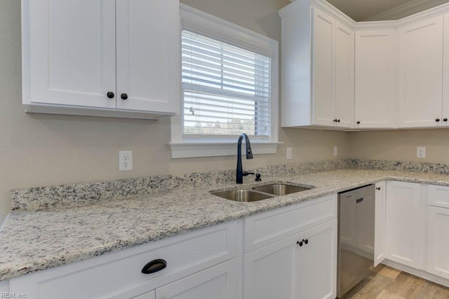 kitchen featuring stainless steel dishwasher, light stone countertops, light wood-style flooring, white cabinets, and a sink