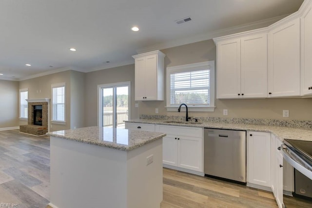 kitchen featuring crown molding, a kitchen island, visible vents, appliances with stainless steel finishes, and a sink