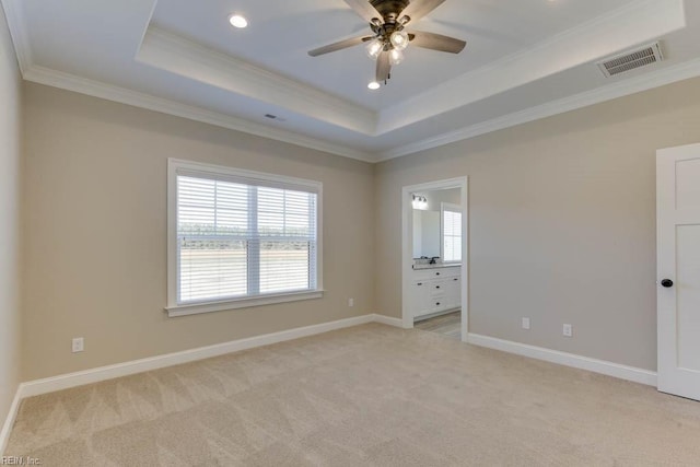 unfurnished room with a raised ceiling, light colored carpet, ornamental molding, and visible vents