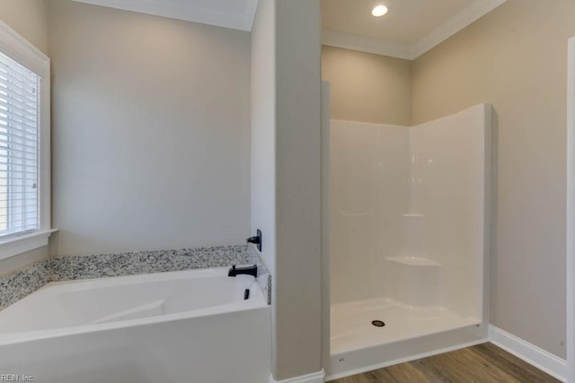 bathroom with baseboards, crown molding, a bath, a shower, and wood finished floors