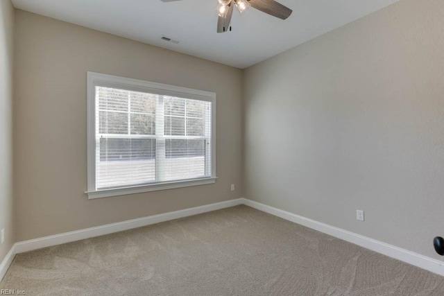 spare room with light carpet, ceiling fan, baseboards, and visible vents