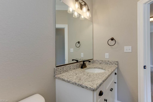 half bath featuring toilet, vanity, and a textured wall