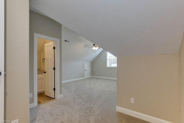 additional living space featuring visible vents, light colored carpet, ceiling fan, and lofted ceiling
