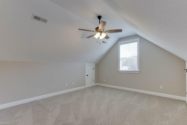 bonus room with ceiling fan, light colored carpet, visible vents, lofted ceiling, and baseboards