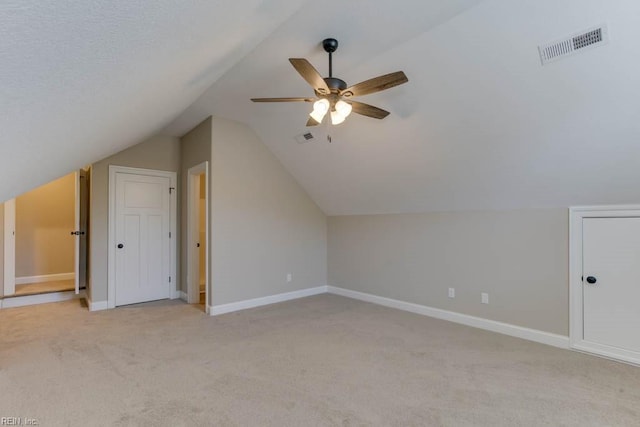 additional living space with a ceiling fan, vaulted ceiling, visible vents, light carpet, and baseboards