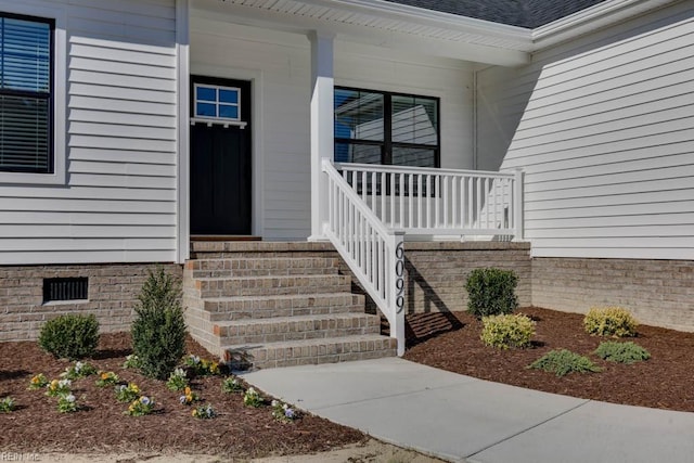 property entrance featuring crawl space, a shingled roof, and covered porch