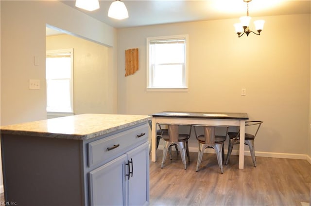 kitchen with a chandelier, decorative light fixtures, baseboards, and light wood-style flooring