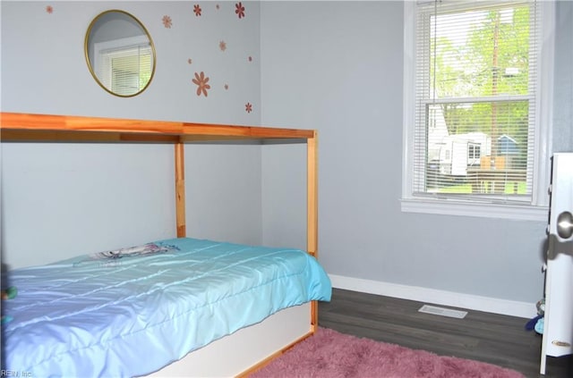 bedroom with visible vents, baseboards, and wood finished floors