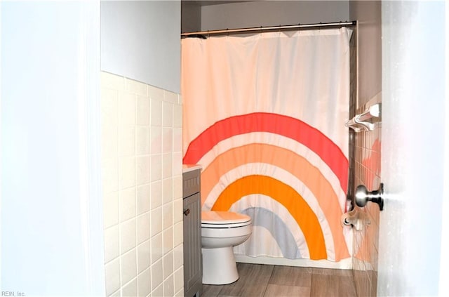 bathroom with tile walls, toilet, wood finished floors, and a shower with curtain