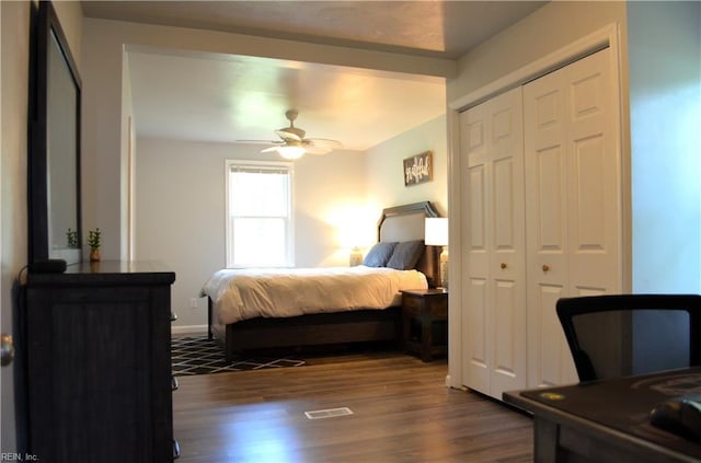 bedroom featuring dark wood-style flooring, a closet, visible vents, and ceiling fan