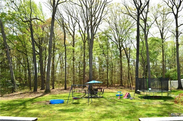 exterior space with a trampoline, a playground, and a lawn