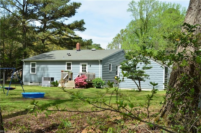 back of property with central AC unit, a deck, a trampoline, a lawn, and a chimney