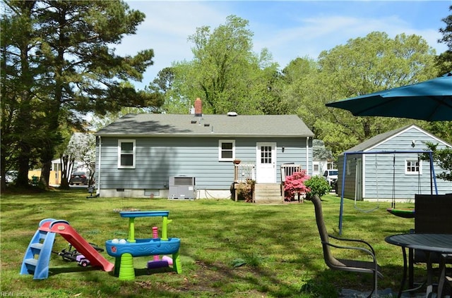 rear view of house featuring crawl space, a chimney, a lawn, an outdoor structure, and central air condition unit