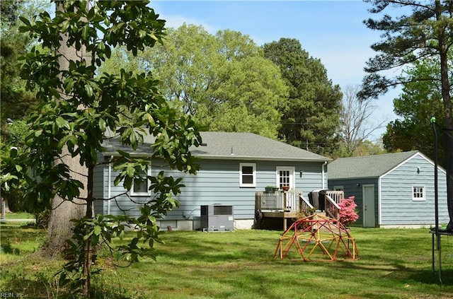 rear view of property featuring central air condition unit, an outbuilding, a deck, and a yard