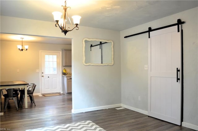 unfurnished dining area featuring an inviting chandelier, baseboards, dark wood-style floors, and a barn door