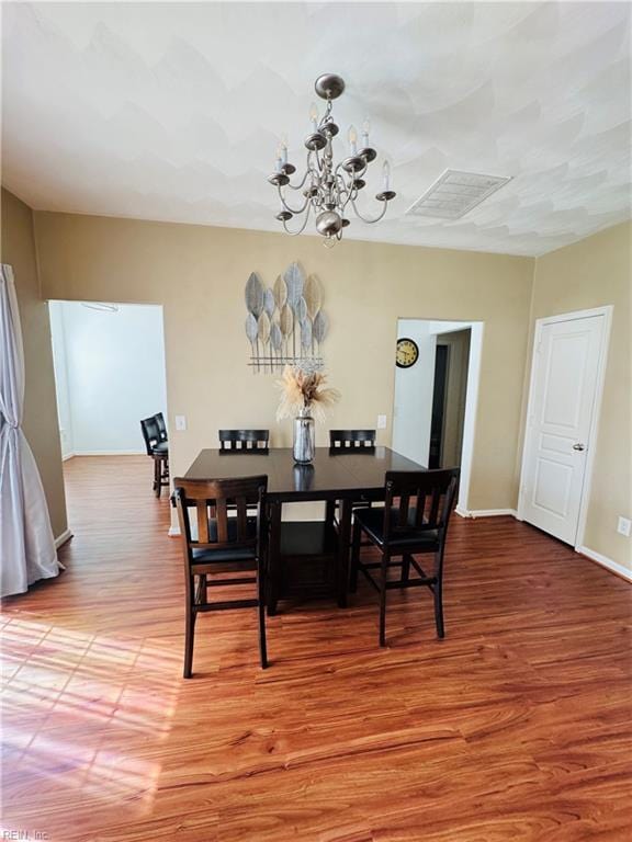 dining space featuring light wood-type flooring, visible vents, baseboards, and a notable chandelier