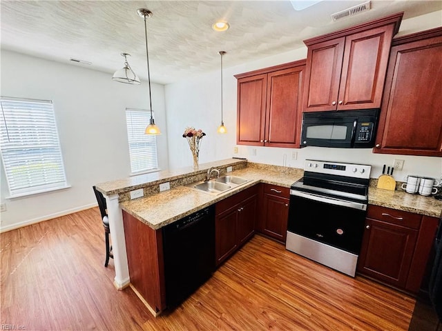 kitchen featuring a sink, black appliances, light wood-style floors, a peninsula, and visible vents