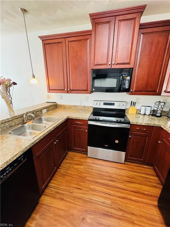 kitchen with a sink, black appliances, reddish brown cabinets, light wood finished floors, and decorative light fixtures