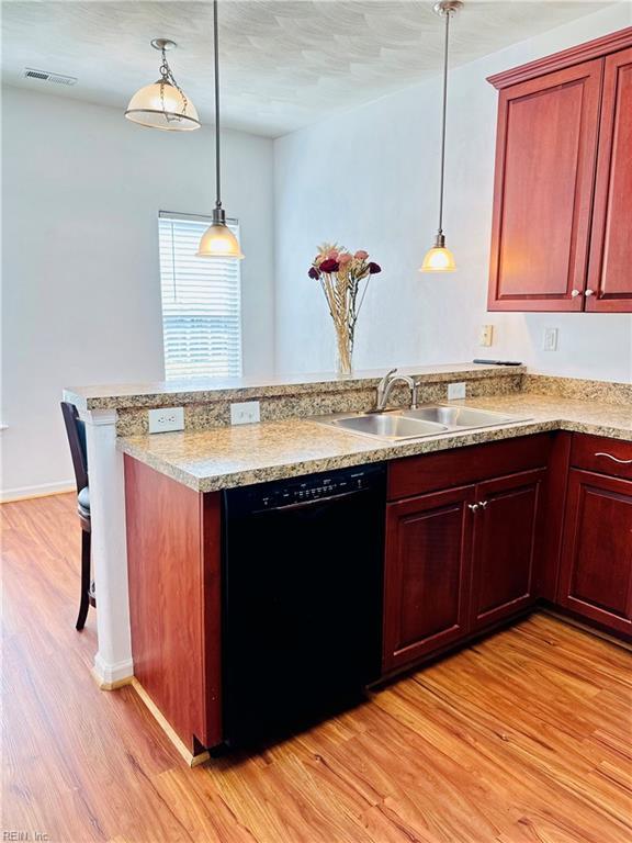 kitchen featuring a sink, light wood-type flooring, reddish brown cabinets, a peninsula, and black dishwasher