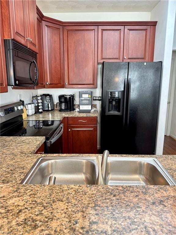 kitchen featuring black appliances, dark brown cabinets, and a sink