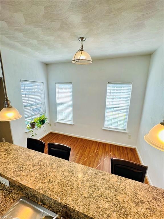 kitchen with decorative light fixtures, wood finished floors, and baseboards