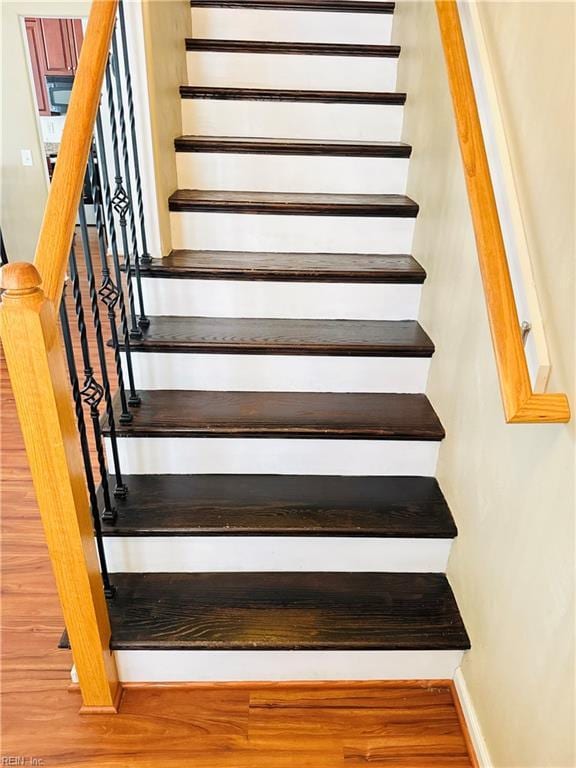 staircase featuring wood finished floors and baseboards