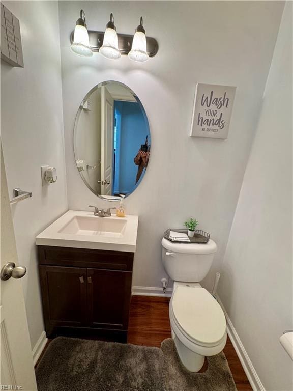 bathroom featuring wood finished floors, vanity, toilet, and baseboards