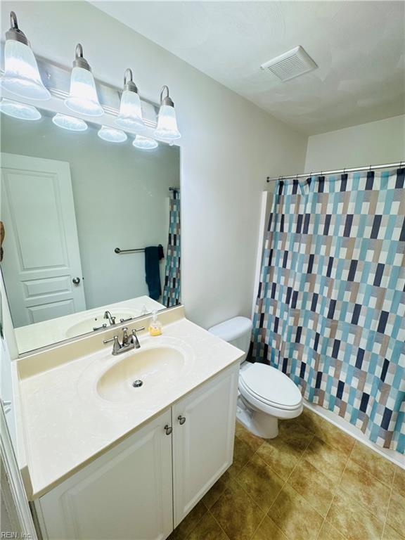 full bath with visible vents, curtained shower, vanity, and toilet