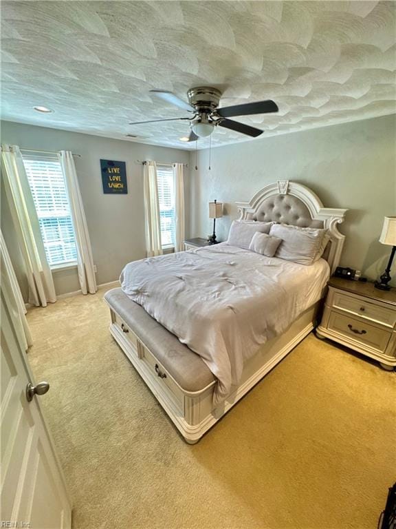 bedroom featuring light carpet, ceiling fan, and multiple windows