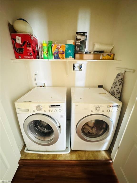laundry area with washing machine and dryer, wood finished floors, and laundry area