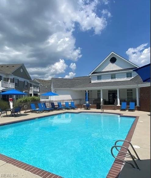 community pool with fence and a patio area