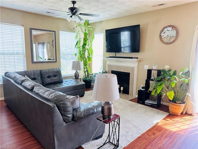 living area with plenty of natural light, wood finished floors, visible vents, a fireplace, and ceiling fan