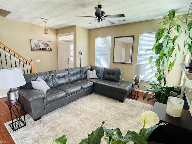 living area with stairway, a healthy amount of sunlight, wood finished floors, and visible vents