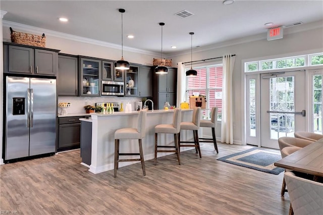 1208 Kings Land Ct, Williamsburg, VA 23185 - kitchen featuring a breakfast bar, decorative light fixtures, backsplash, appliances with stainless steel finishes, and visible vents