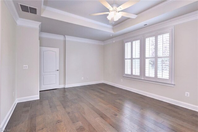 spare room with a tray ceiling, dark wood finished floors, baseboards, visible vents, and a ceiling fan