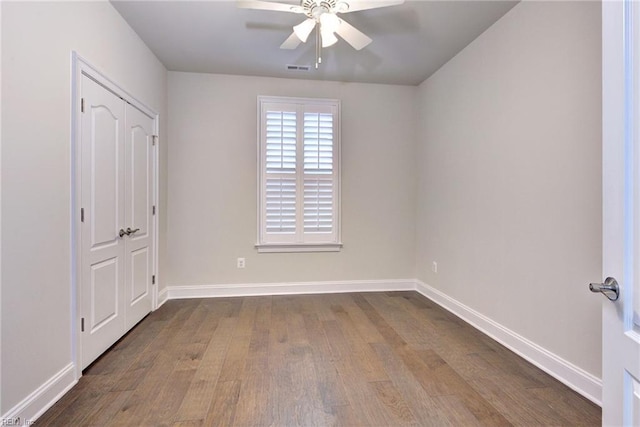 unfurnished bedroom with dark wood finished floors, visible vents, baseboards, and ceiling fan